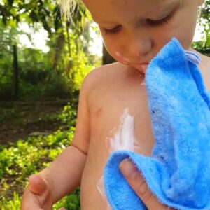 toddler with white mess on tummy with blue cloth wipe