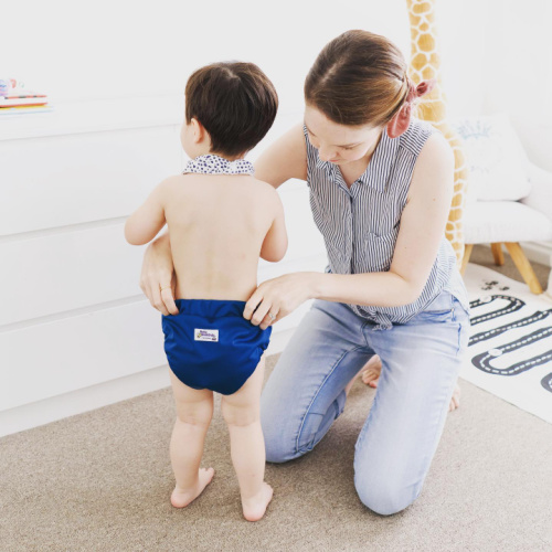 toddler putting on pull up training pants in blue with mum