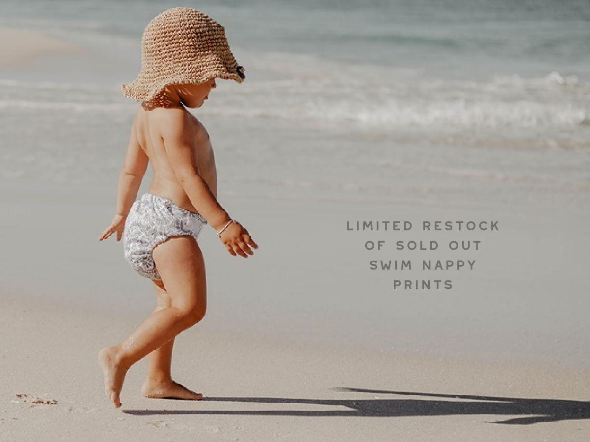reusable swimming nappy on toddler walking on beach