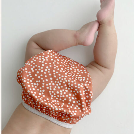 rusty and white spotted nappy cover on bag showing his legs.